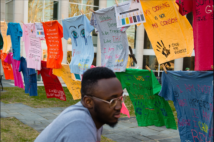 student viewing the shirts as part of the Clothesline Project