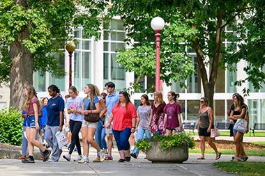 a group of student visitors walking through the Oak Grove