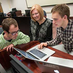 Two students working with their professor