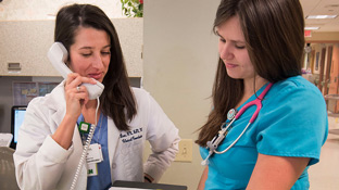 two female nurses talk at the nursing desk