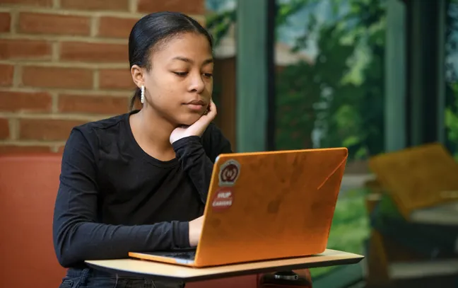 a student sitting at a desk studying on a laptop