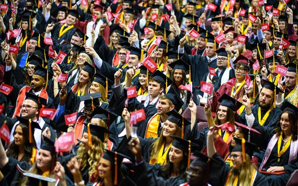 a group of graduates at commencement holding up IUP flags