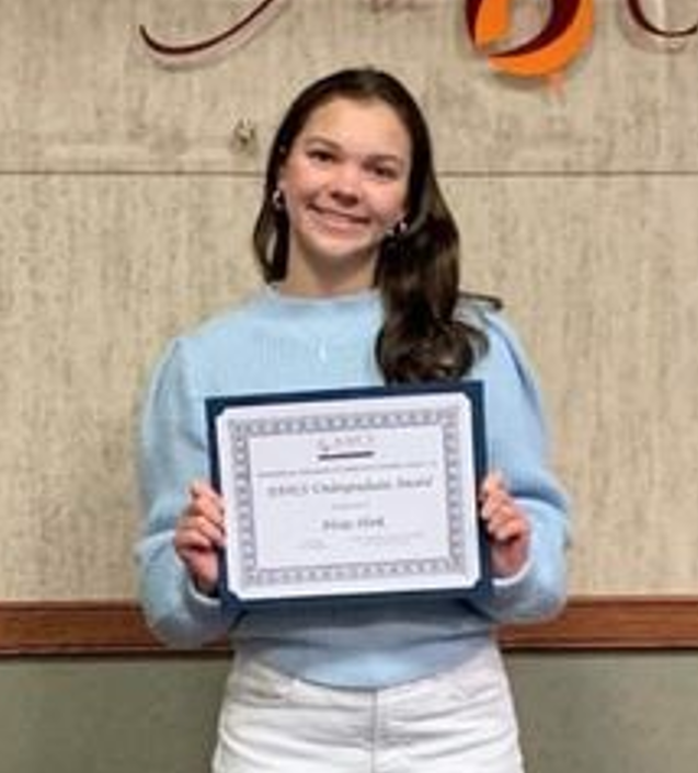 Alexis Shirk smiling and holding her scholarship award