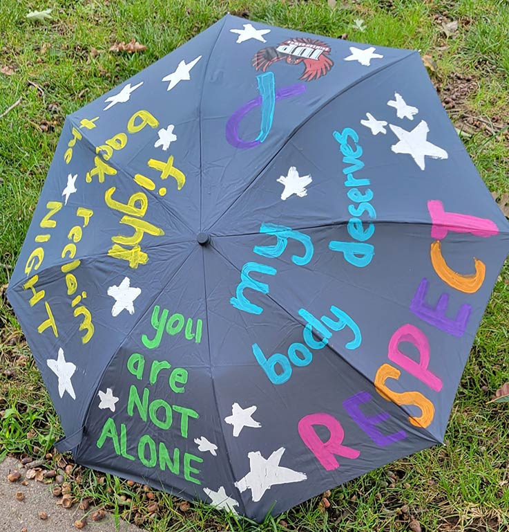 RAINN Day, a open pink umbrella with inspirational messages written on it, in the Oak Grove grass