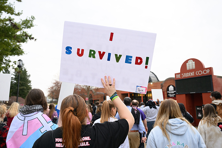 photo of a student holding a sign that says "I survived"