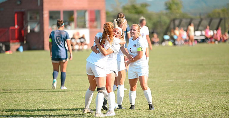 IUP student athletes hugging each other on the field and smiling