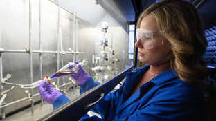 female student working in a lab with a beaker