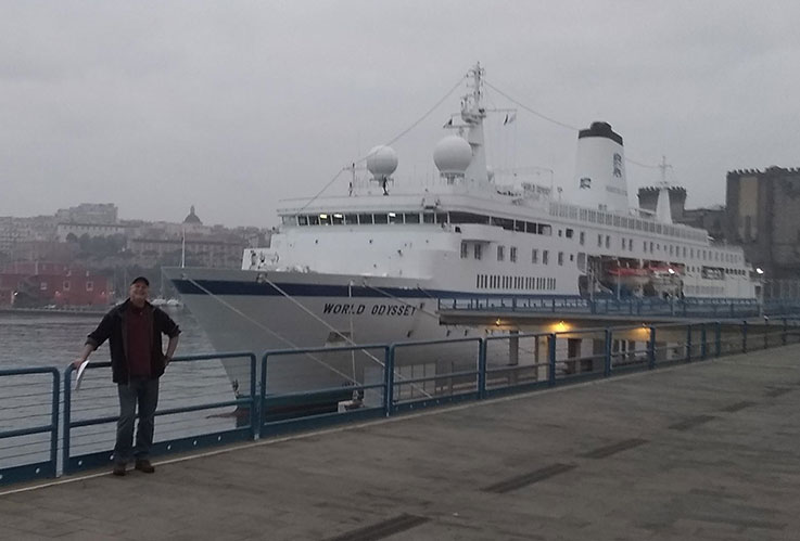 Tim Hibsman on the dock with the World Odyssey moored behind him in Naples, Italy.