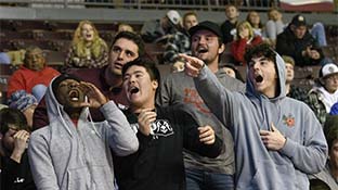 students cheering in the bleachers of a basketball game