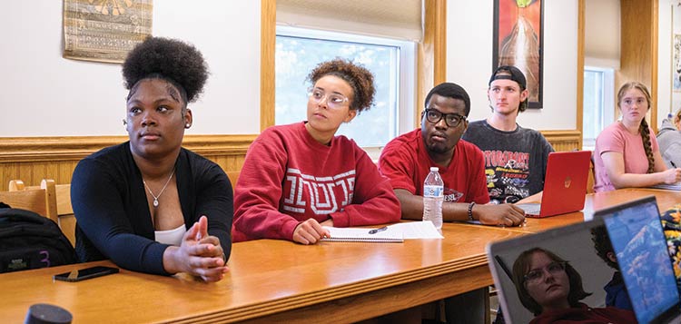 Honors College students at a table in the Great Hall listening to a speaker