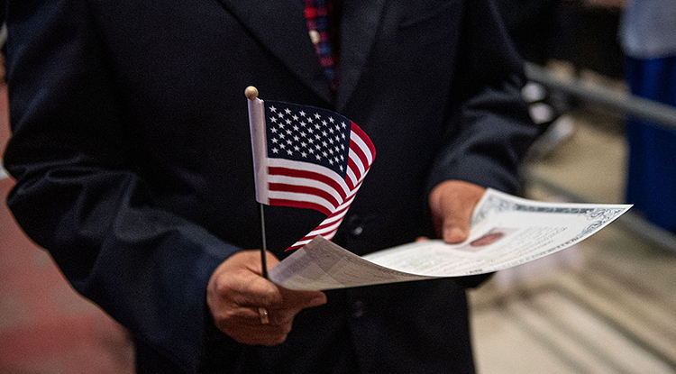 A person's hand holding a small American flag