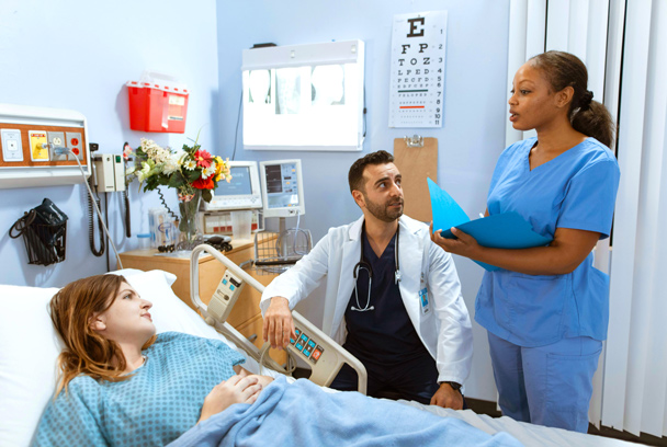 nurse, doctor, and patient in a hospital bed talk in a hospital room