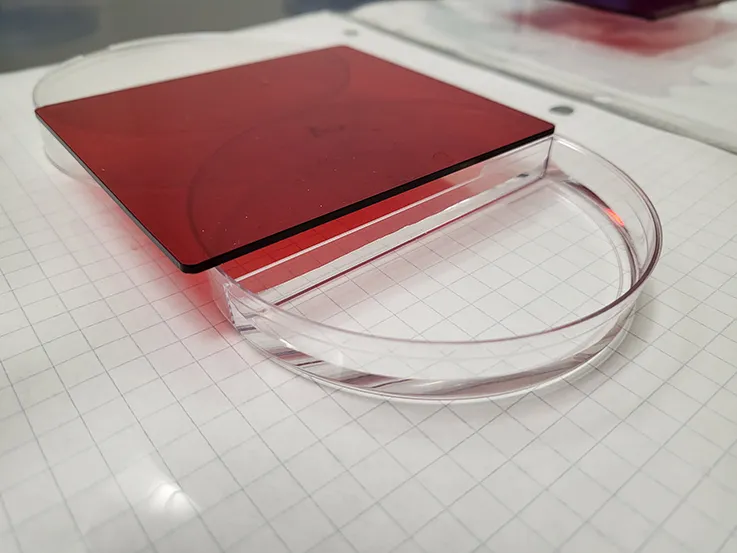 a petri dish with a red lit sitting on a table on top of grid paper