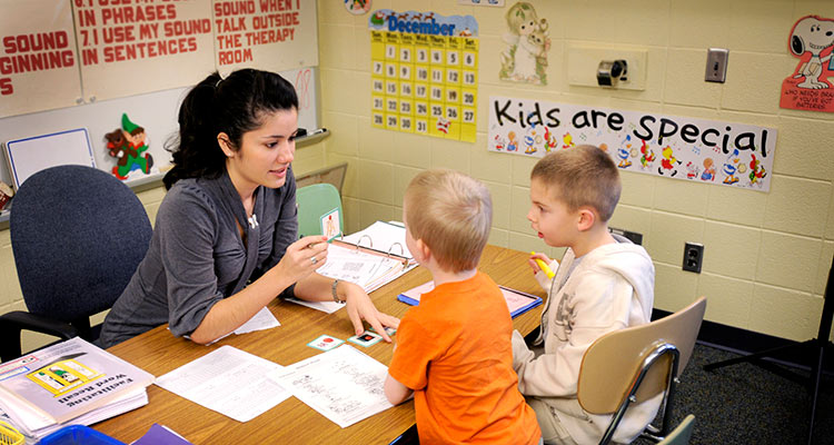 A student teacher helps young students with speech exercises.