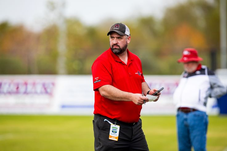 Men's Club Rugby Head Coach Erwin on the field checking his notes.