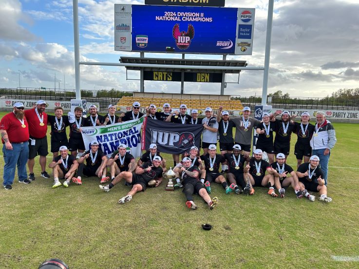 The Men's Rugby Club and coaches pose with a their winning trophy.