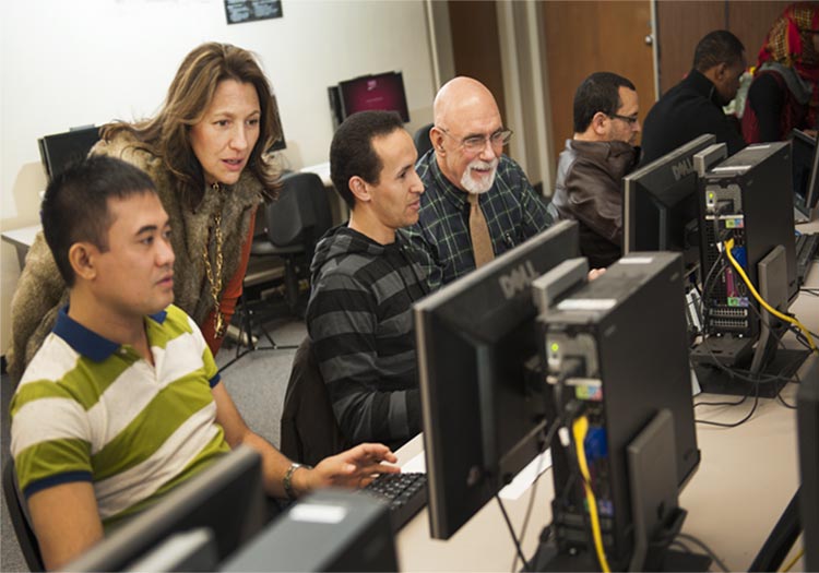 Two professors helping adult students on the computer