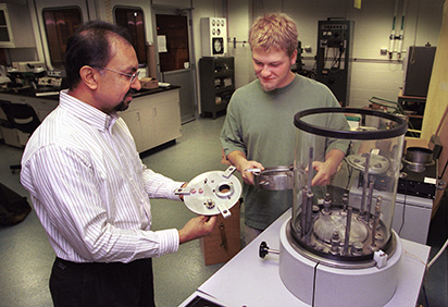 A physics professor works with a student in the lab